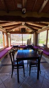a table and chairs in a room with windows at Hostería Terrazas de la Posta in Purmamarca