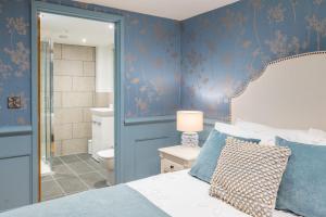 a bedroom with blue walls and a bed and a bathroom at Hillside Barn in Gimingham +36 photos