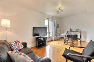 a living room with a couch and a tv and a table at Le Franche in Châtillon-sur-Loire