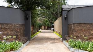 a walkway between two brick fences with plants at Lombard Manor in Pretoria