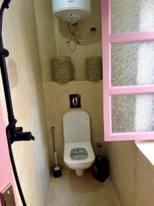 a small bathroom with a toilet and a window at Surf house in Essaouira