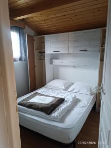 a bed in a room with white walls and wooden ceilings at La Taillade de Montségur location de Chalets en bois in Fougax-et-Barrineuf +24 photos