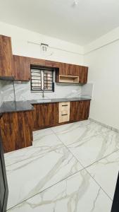 an empty kitchen with marble floor and wooden cabinets at MIRACLE inn NEAR AL-AMEEN COLLEGE in Alwaye