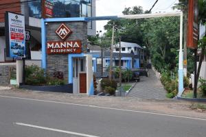a sign for a manima restaurant on the side of a street at Manna Residency in Kottayam