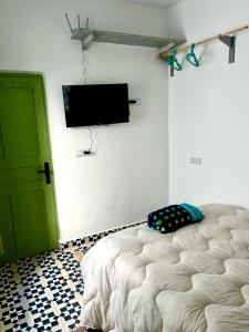 a bedroom with a bed and a flat screen tv at Surf house in Essaouira