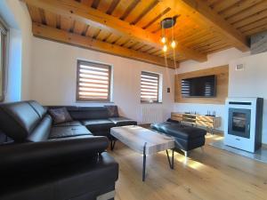 a living room with a leather couch and a table at Chata Valeriana Liptov in Ižipovce