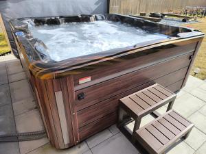 a hot tub with a wooden bench next to a chair at Chata Valeriana Liptov in Ižipovce