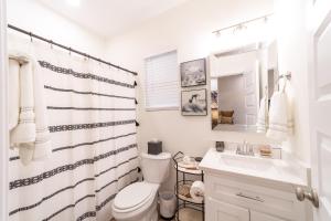 a white bathroom with a toilet and a sink at Palmetto Place, Charming Saint Simons Bungalow in Saint Simons Island +11 photos