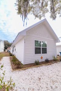 a white house with a driveway in front of it at Palmetto Place, Charming Saint Simons Bungalow in Saint Simons Island