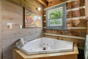 a white tub in a wooden bathroom with a window at Rustic Mountain Escape with Fire Pit and Mountain Views-Cabin 1 in Fancy Gap +31 photos