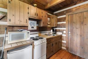 a kitchen with wooden cabinets and a stove and a microwave at Rustic Mountain Escape with Fire Pit and Mountain Views-Cabin 1 in Fancy Gap
