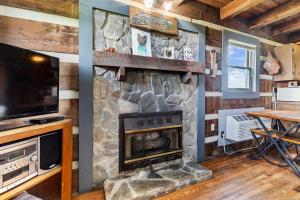 a living room with a stone fireplace and a tv at Rustic Mountain Escape with Fire Pit and Mountain Views-Cabin 1 in Fancy Gap