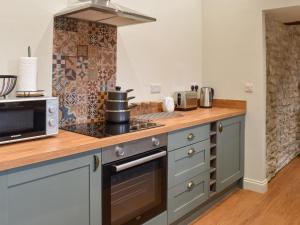 a kitchen with a stove top oven next to a microwave at The Cowshed - Uk50283 in Earl Sterndale