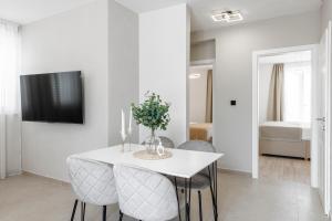 a white dining room with a white table and chairs at Cozy Corner 49 in Cavtat