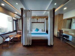 a bedroom with a canopy bed and a desk at Hotel Dewan Palace in Dharmsāla