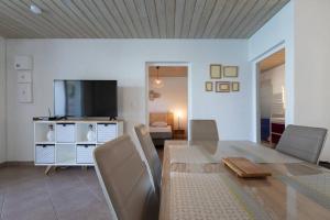 a living room with a dining table and a television at L' Amandava in Petite Île