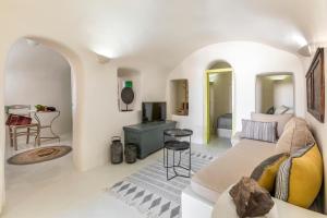 a white living room with a couch and a tv at Casa Grande Santorini in Megalochori
