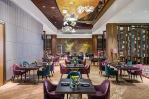 a restaurant with tables and chairs and a chandelier at MORAZEN Surabaya in Surabaya