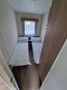 a small room with two beds and a window at Swanage Caravan in Swanage