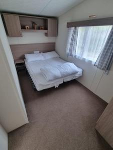 a small bedroom with a bed and a window at Swanage Caravan in Swanage