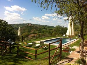 a swimming pool with chairs and an umbrella next to it at B&B Cà Biocco in Sogliano al Rubicone