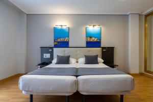 a bedroom with two beds and two paintings on the wall at Chateau La Roca in Sancibrián