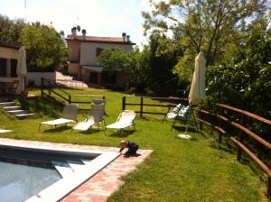 a man kneeling on the grass next to a pool at B&B Cà Biocco in Montetiffi