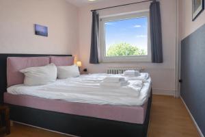 a bedroom with a bed with white sheets and a window at fewo1846 - Ostseebad - Apartment mit 2 Schlafzimmern und Meerblick in Flensburg