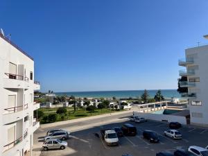 a parking lot with cars parked in front of a building at Pérola VerdeMar in Quarteira