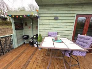 a wooden deck with a table and chairs on a house at The Hideaway Pod in Chelmsford