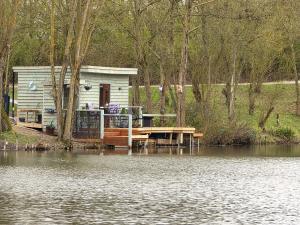 a house on a dock next to a body of water at The Hideaway Pod in Chelmsford