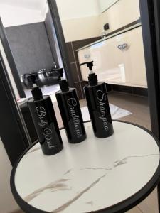 three black shampoo bottles sitting on a table at Artemide Resort, Suite Spa Elysia in Lido Di Fondi