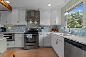 a kitchen with white cabinets and a sink and a window at 2444 - Sea Forever in Duck