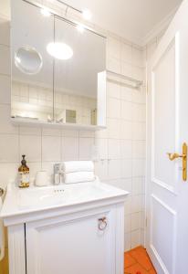a white bathroom with a sink and a mirror at Beach Bungalow Sylt 1 in Dikjendeel