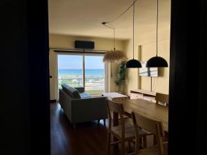 a living room with a dining room table with a view of the ocean at Pérola VerdeMar in Quarteira