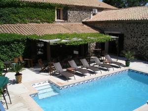 a pool with chairs and tables and a house at La Bergerie Du Cap in Cap d'Agde