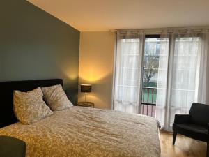 a bedroom with a bed and a window and a chair at STUDIO PROCHE PARIS VERSAILLES in Villennes-sur-Seine