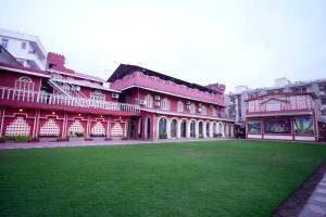 a red building with a green lawn in front of it at Canalta Hotel Restaurant Bar in Jaipur