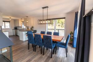 a dining room and kitchen with a wooden table and blue chairs at Chalet Isatis - SPA - Access to the Lake in Saint Come