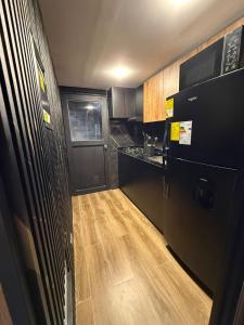 a small kitchen with black cabinets and a wooden floor at Casa ibague in Ibagué