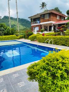 a villa with a swimming pool in front of a house at GLAMPING EL PARAÍSO in Sasaima