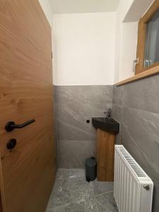 a bathroom with a sink and a wooden door at Appartement Steinblick -Obinghof- in Maishofen +31 photos