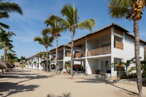 a building on the beach with palm trees at Punta Sal Suites & Bungalows Resort in Canoas de Punta Sal