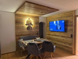 a dining room with a table and a tv on a wall at Appartement Steinblick -Obinghof- in Maishofen