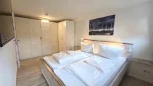 a bedroom with a white bed with white sheets and pillows at Ferienwohnung "Ostseebrise" in Wendtorf in Wendtorf