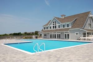 a house with a swimming pool in front of a house at 2437 - Sandpiper Station in Duck