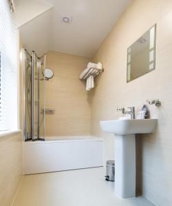 a bathroom with a shower and a sink and a tub at The Maple Manor Hotel and guest holiday parking in Crawley