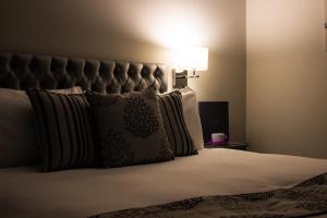 um quarto com uma cama com almofadas e um candeeiro em The Maple Manor Hotel and guest holiday parking em Crawley