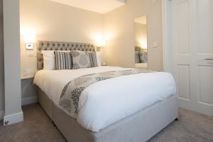 ein Schlafzimmer mit einem großen weißen Bett und einem Spiegel in der Unterkunft The Maple Manor Hotel and guest holiday parking in Crawley