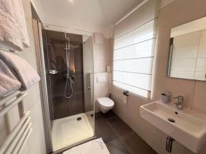 a bathroom with a shower and a toilet and a sink at Hotel Casa Borghese in Senningerberg